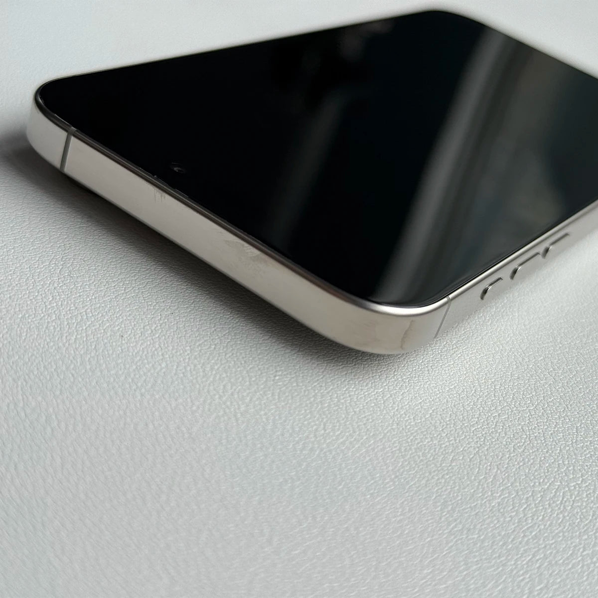 Close-up of Apple iPhone 16 Pro Max 256GB unlocked showing metallic edge and black screen on white surface