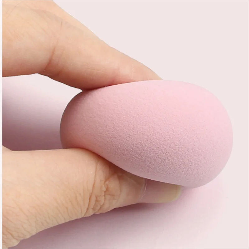 Pink makeup sponge from Merit Sell wet and dry makeup blender set held between fingers