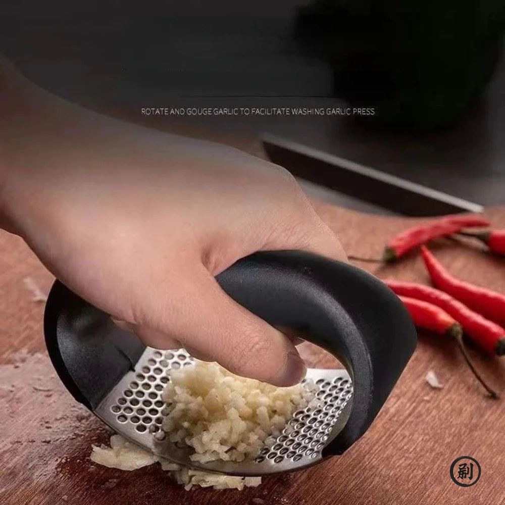 Merit Sell stainless steel garlic press with ergonomic black handle crushing fresh garlic on wooden board
