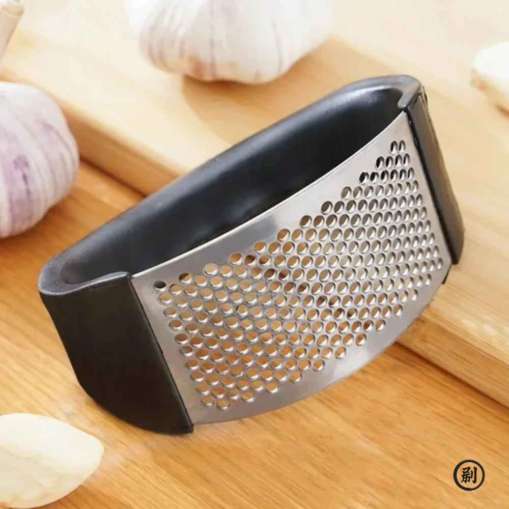 Merit Sell stainless steel garlic press with ergonomic black handles on wooden surface