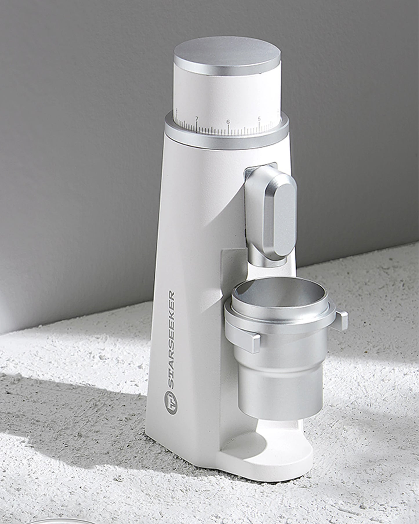 Merit Sell electric coffee grinder with titanium burrs in white and silver design on textured surface