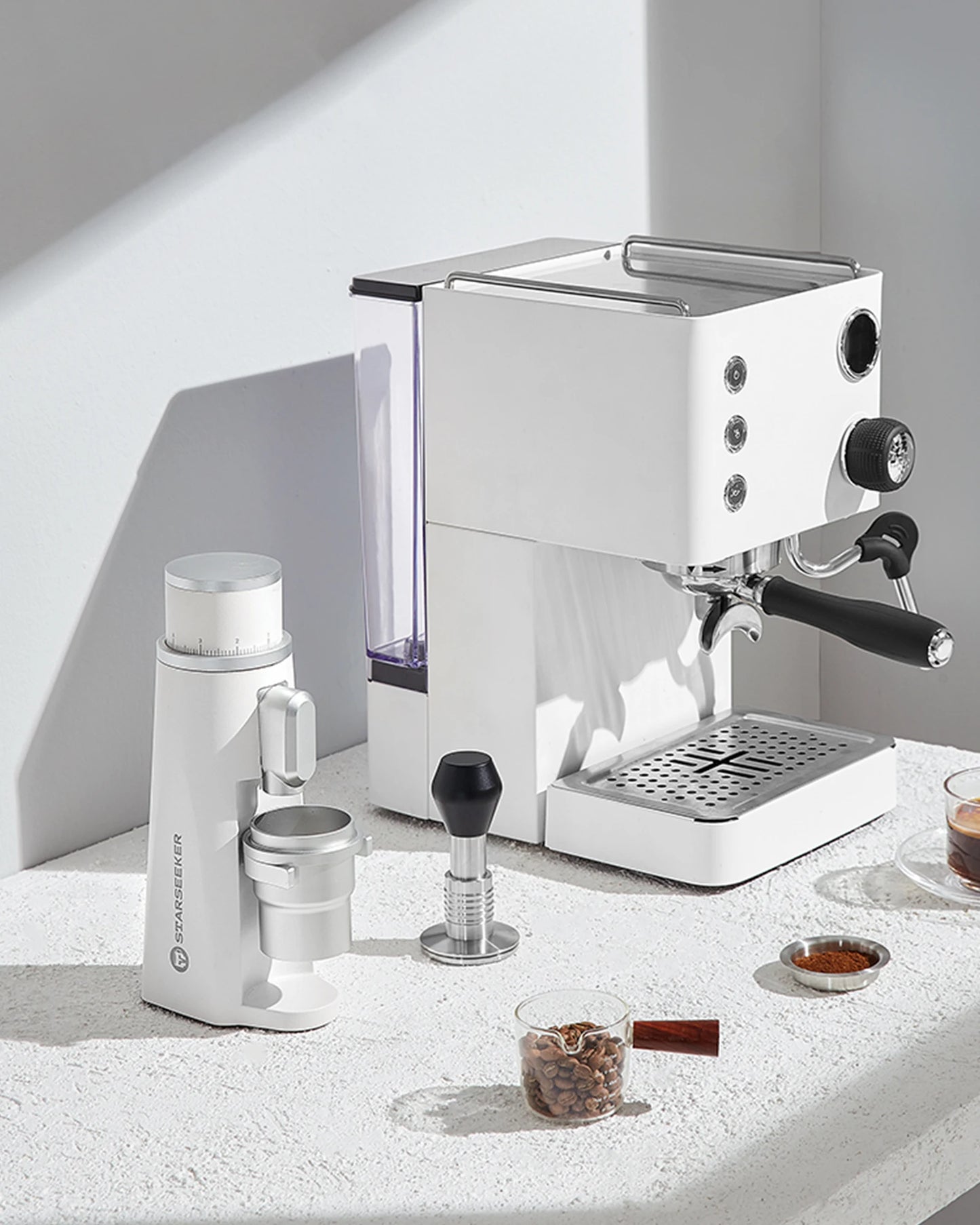 Merit Sell electric coffee grinder with titanium burrs next to a white espresso machine on countertop