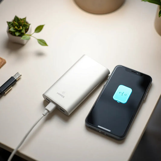 Compact power bank connected to a smartphone with a charging cable on a clean desk