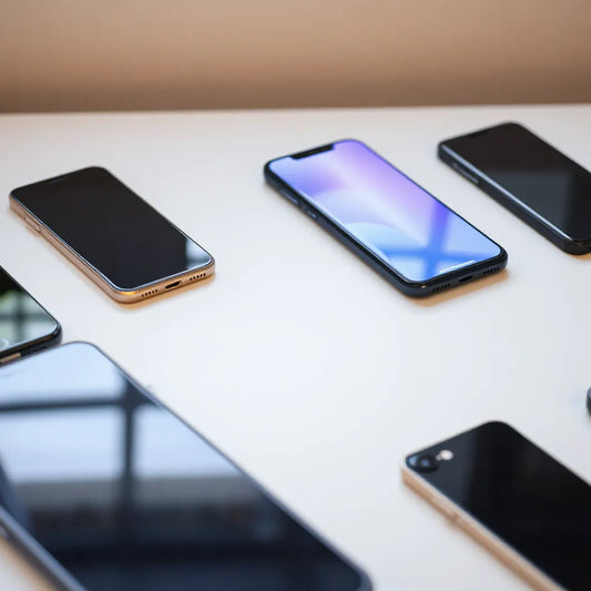 Multiple latest smartphones displayed on a minimalist desk with bright screens and sleek designs