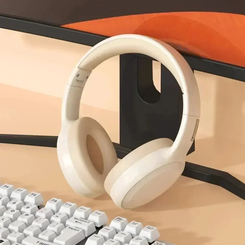 White headphones on a desk with a keyboard and computer monitor in the background