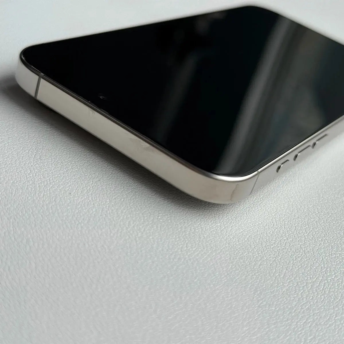 Close-up of Apple iPhone 16 Pro Max 256GB unlocked with sleek metallic edge and black screen on white surface