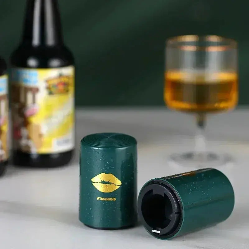 Merit Sell magnetic automatic bottle opener in green with gold lips design on a countertop with drinks in the background