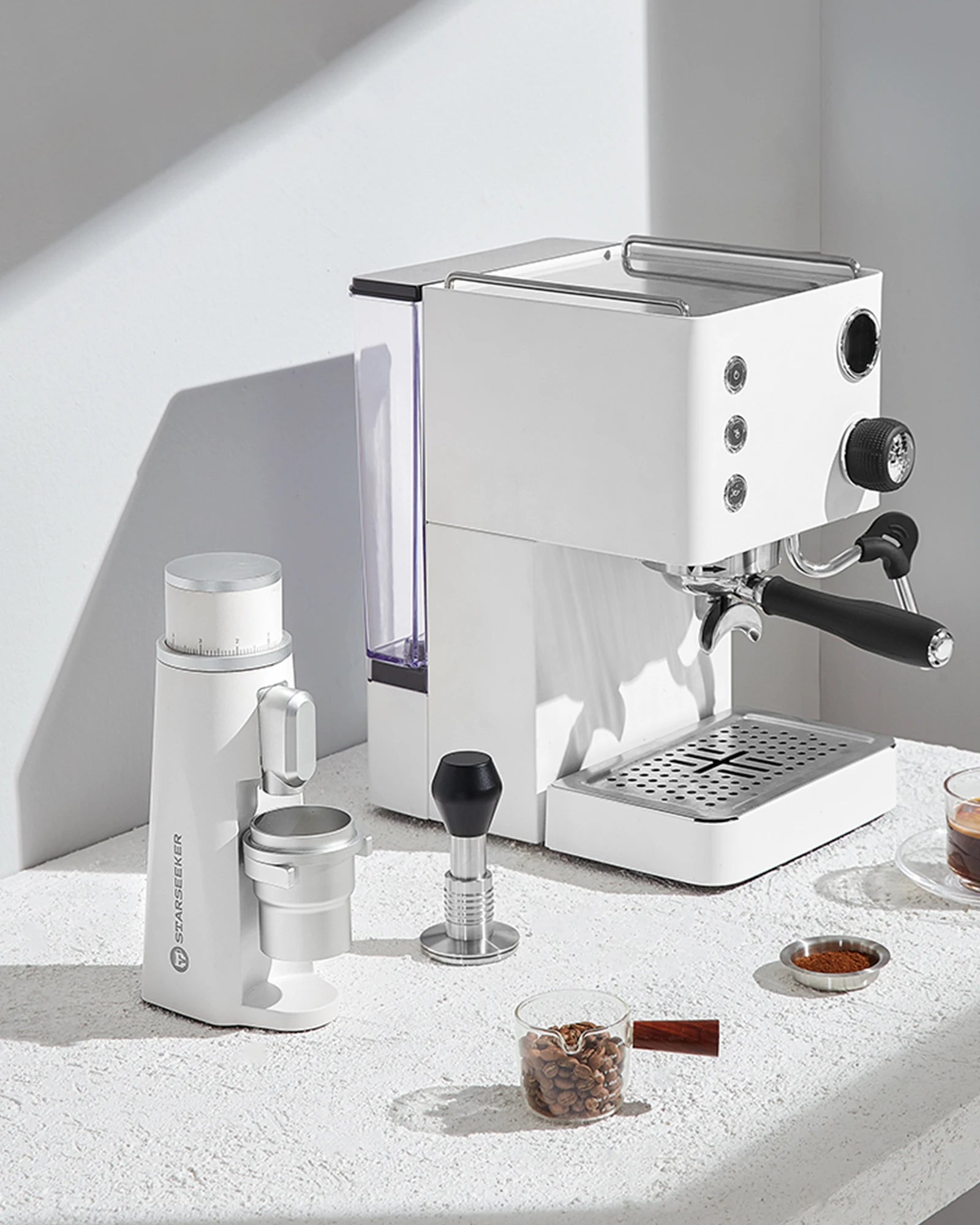 Merit Sell electric coffee grinder with titanium burrs next to a white espresso machine on countertop